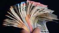 Hand holding a large pile of euro banknotes.