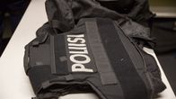 Black body armour vest with the word "poliisi" emblazoned in white on it.