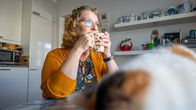 Eeva Lätti istuu keittiönpöydän ääressä kahvikuppi käsissään. 