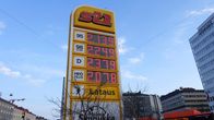 Tall, yellow petrol station sign with prices for various types of fuel.