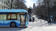 Bussi ajaa kadulla. Taustallan näkyy patsas ja Lahden kaupungintalo sekä ihmisiä kadulla.