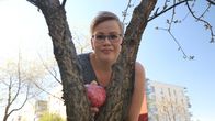 Nainen asettaa kauniisti maalattua kiveä oksanhaaraan.