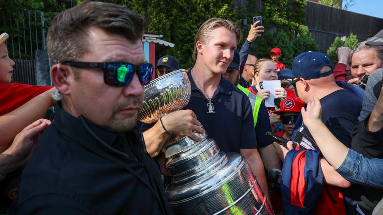 Jääkiekkoilija Anton Lundell kantaa Stanley Cup -pokaalia fanien ympäröimänä.