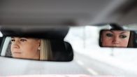 Kahden naisen peilikuvat autokoulun auton sisäpeileissä.