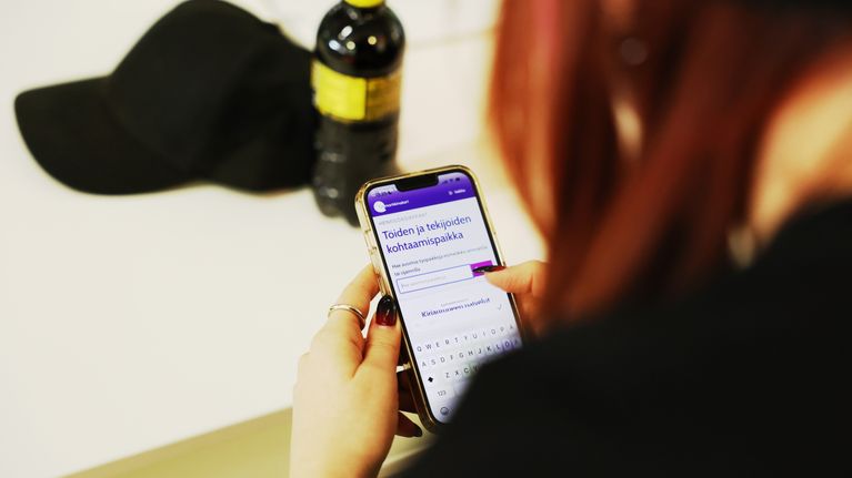 Nainen katsoo puhelimesta työvoimapalvelusivuja.