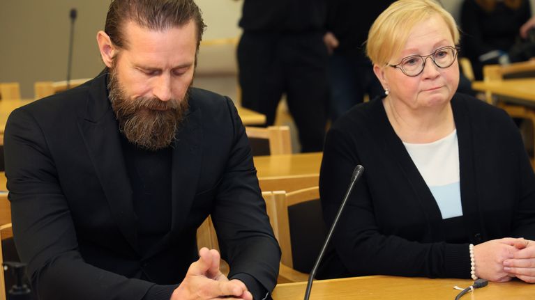 Mustiin pukeutunut, parraskas laulaja Lauri Tähkä ja asianajajansa Riitta Leppiniemi lähikuvassa istumassa oikeudessa päydän takana. Tähkän katse luotu alas, kädet yhdessä pöydällä.