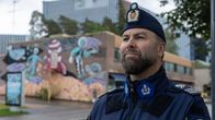 Suomalainen poliisi seisoo kadulla. Taustalla värikäs seinämaalaus.