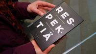 Personen håller i en bok med titeln "Respektiä".