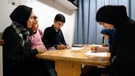 Äiti ja lapset istuvat keittiön pöydässä ja lapset piirtävät. Vasemmalta Äiti Dania Al-Zaghaleel (35v), sylissä Hanin Abuzaid (6v),  Omar Abuzaid (14v), oikealla edessä Tahira Abuzaid (13) ja Tahiran takana  Jana Abuzaid (8v).