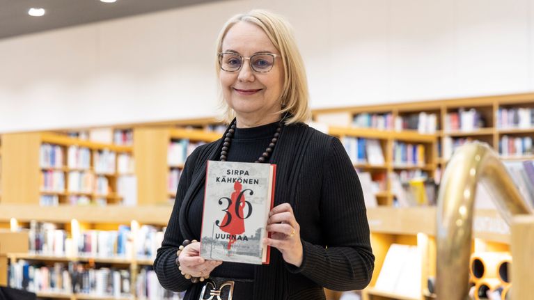 Kirjastotoimenjohtaja Päivi Savonainen pitää Finlandia voittajateosta sylissään.