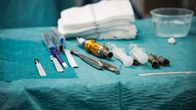 Esillä on kirurgisia instrumentteja ja tarvikkeita leikkaussalissa, mukaan lukien skalpelleja, ruiskuja ja neuloja.