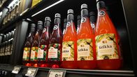 8% alkoholijuomapulloja ruokakaupan hyllyllä. Punaisissa pulloissa lukee Vadelma Booli, ja oranssin värisissä pulloissa Kelkka.