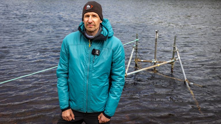 Tutkija seuraa vesistön mittauslaitteiston toimivuutta joen rannalla.  +
