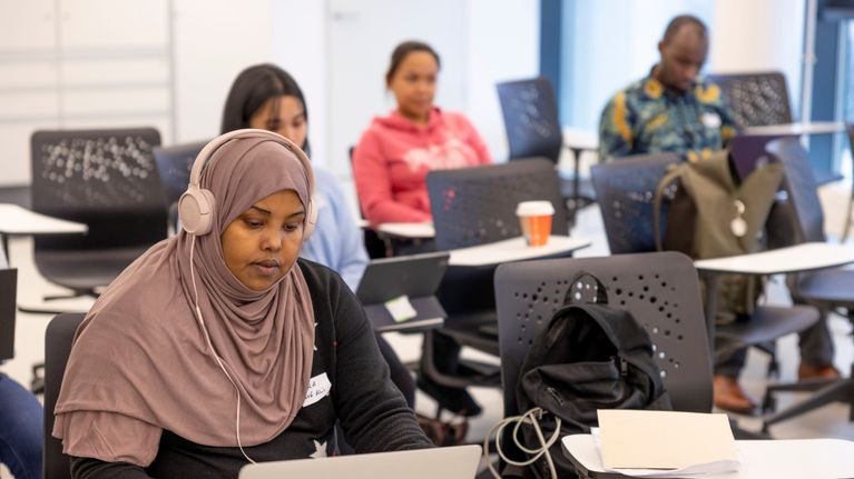 Photo shows people sitting in a classroom.