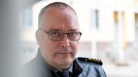 Nahkatakkinen mies seisoo rakennuksen vierustalla.