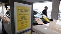 Yellow sales sign promoting car leasing deal, standing in front of a white car