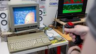 Pöydällä harmaa Atari-keskusyksikkö ja sen päällä näyttö, jossa menee vanha Stardust-peli.