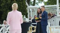 Presidentti Alexander Stubb hymyilee mikrofoni kädessään. Vieressä seisoo rouva Suzanne Innes-Stubb.