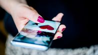 Hand with brightly coloured fingernails holding a smartphone.