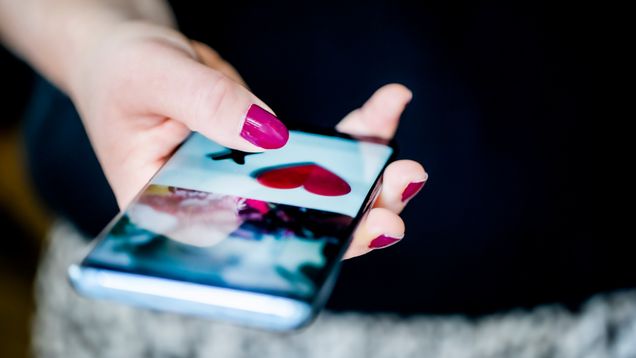 Hand with brightly coloured fingernails holding a smartphone.