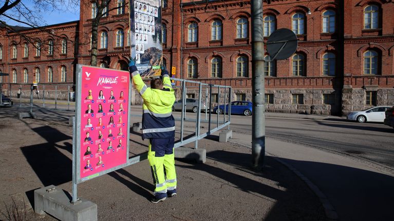 Työntekijä asettaa paikalleen vaalimainosta.