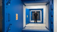 The heavy blue doors of a civil defence shelter, with a man seen standing in the background.