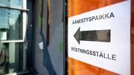 Kyltti ulkoseinässä, jossa lukee "äänestyspaikka". Kyltin keskellä on iso nuoli kuvan oikealta vasemmalle. 