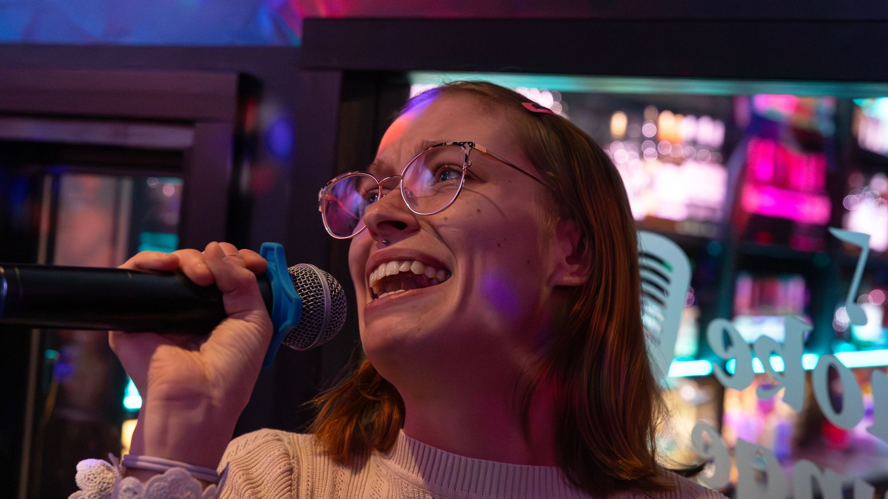 Nainen laulaa mikrofoniin karaokea.