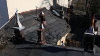 Flera skorstenar och ventilationsrör syns på taken till äldre byggnader.