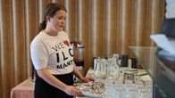 Työharjoittelija Milla Turpiainen siivoaa hotellin aamiaispöytää. 