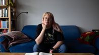 Matilda Halttunen istuu sinisellä sohvalla asunnossaan. Hän lepuuttaa päätä kädellään ja katsoo kameraan.