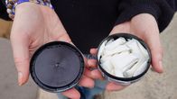 Någon håller en öppen burk med nikotinpåsar, så kallat vitt snus, i handen så att dosan är i den ena och locket i den andra handen.