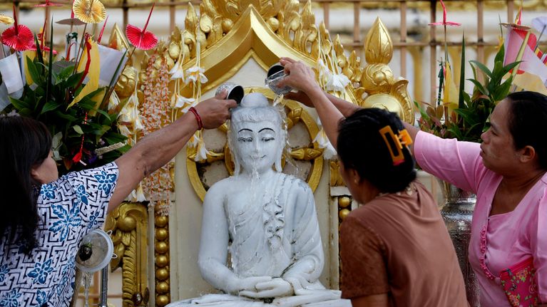 Ihmiset antavat vettä Buddha-patsaalle Myanmarin suurimmassa kaupungissa Yangonissa.