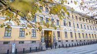 Syksyisten kellastuneiden puunlehtien takaa näkyy keltainen rakennus.