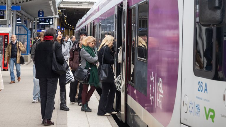 Passagerare stiger i ett lokaltåg på en station.