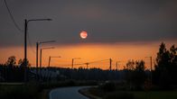 Savun punaiseksi värjäämä aurinko ja kylänraittia. 
