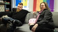 Vasemmalla  Oulu Priden hallituksen jäsen Petri Keskitalo ja oikealla Oulu Priden päätuottaja Martu Väisänen. Taustalla näkyy lautapelikokoelma ja seinällä roikkuvat lippu sekä sateenkaariviiri. Lisäksi sohvalla on pehmolelu, joka esittää jäätelötötteröä.