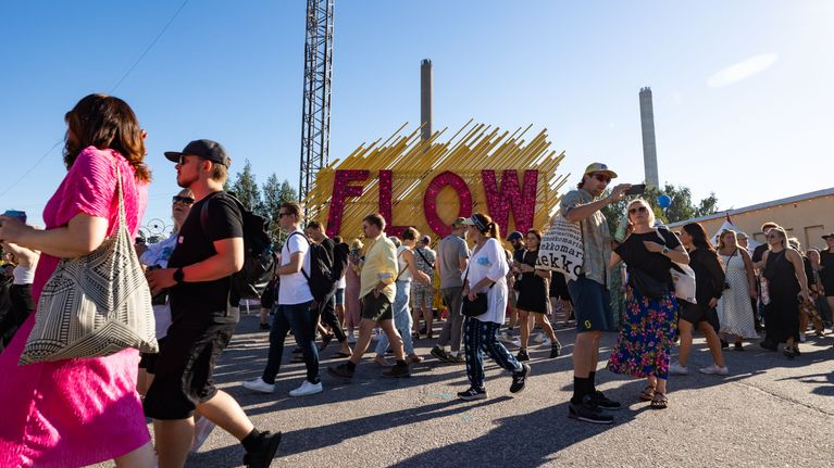 Flow-festvaalin flow-kyltti, jonka edestä kulkee lukuisa joukko ihmisiä.