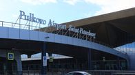 Blue-grey airport building with a sign saying "Pulkovo Airport Saint Petersburg" under a grey sky.