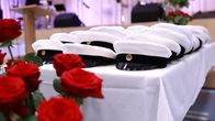 Studentmössor på ett bord redo för utdelning, röda rosor i förgrunden. 
