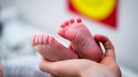 Äiti pitelee vastasyntyneen lapsen jalkoja
