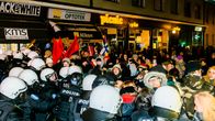 Poliisit työntävät mielenosoittajia kadulla.