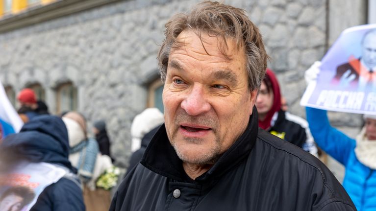 Kimmo Kiljunen haastateltavana. Taustalla ihmisiä ja Putin-juliste ilmaan nostettuna.