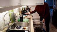 A person loading a dishwasher. 