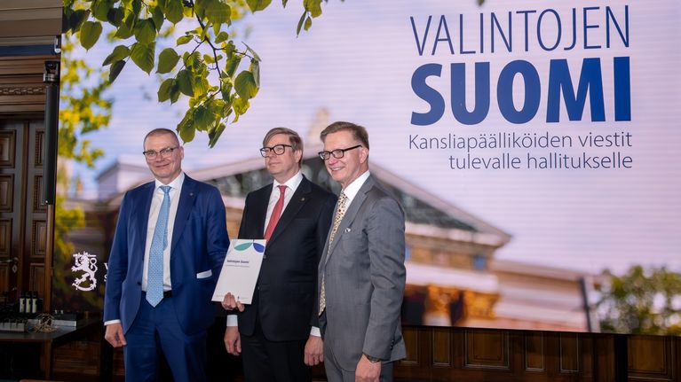 Kolme miestä esittelee raporttia Valintojen Suomi -tilaisuudessa Säätytalolla Helsingissä.