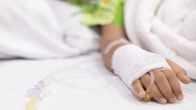A hand in a hospital bed. The hand is bandaged, and the child is on a drip.