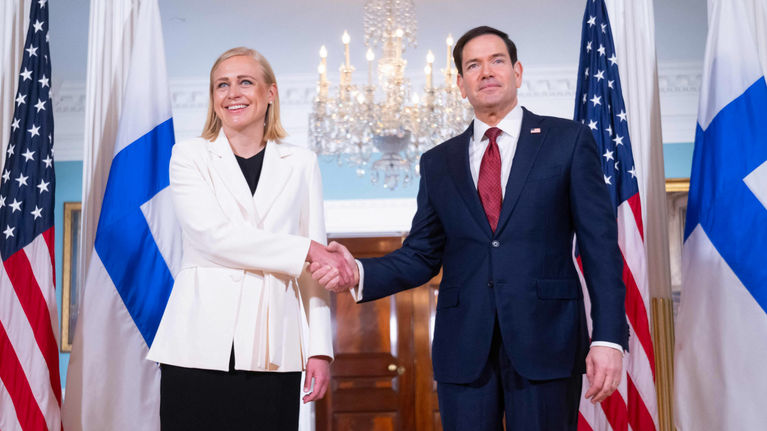 Two formally dressed people, Elina Valtonen and Marco Rubio, shake hands.