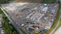 Rakennustyömaa metsäalueen laidalla, keskellä nousevia betonirakenteita ja alueella työmaakoneita.