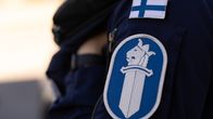 Poliisin hihamerkki, jonka yläpuolella Suomen lippu. 