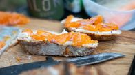 Leikkuulaudalla leipäviipaleiden päällä on rautua, vieressä veitsi.